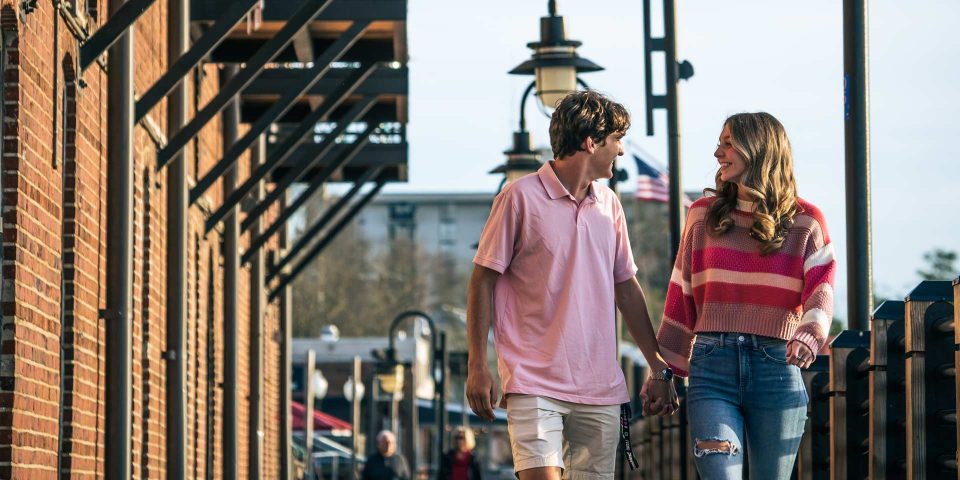 A young couple walking and holding hands in Wilmington, NC