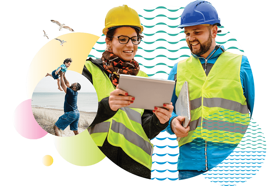 Two employees wearing hardhats and reflective vests looking at a tablet together