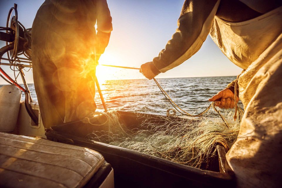 Tow fishermen pulling in a net at sunset