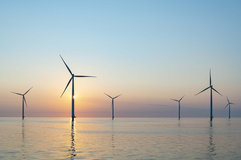 Offshore wind farm with turbines at sunset