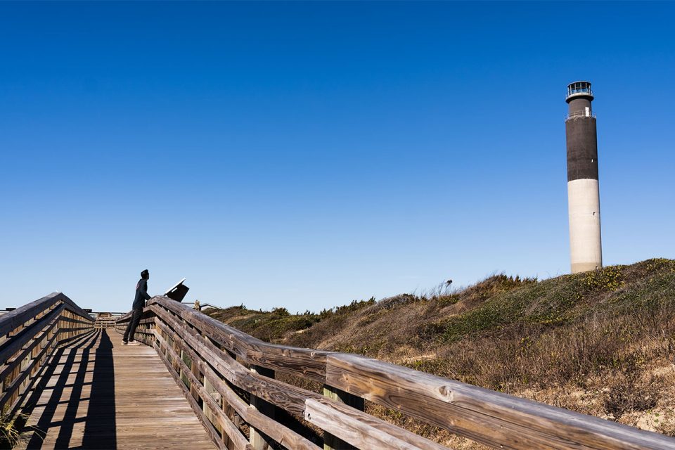 Man on boardwalk looking at lighthouse